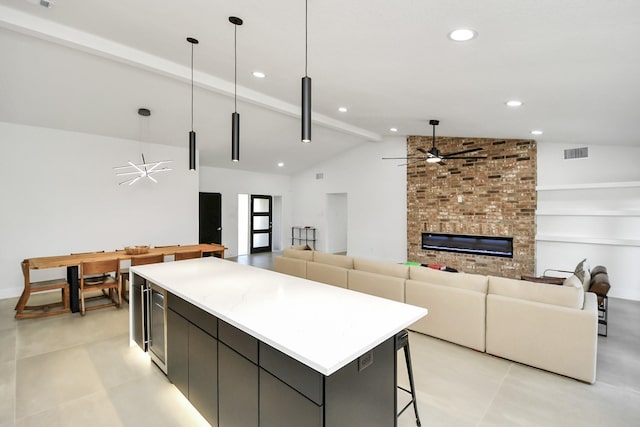 kitchen with decorative light fixtures, vaulted ceiling with beams, a large fireplace, a center island, and ceiling fan