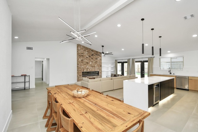 kitchen featuring sink, a center island, hanging light fixtures, stainless steel dishwasher, and a fireplace