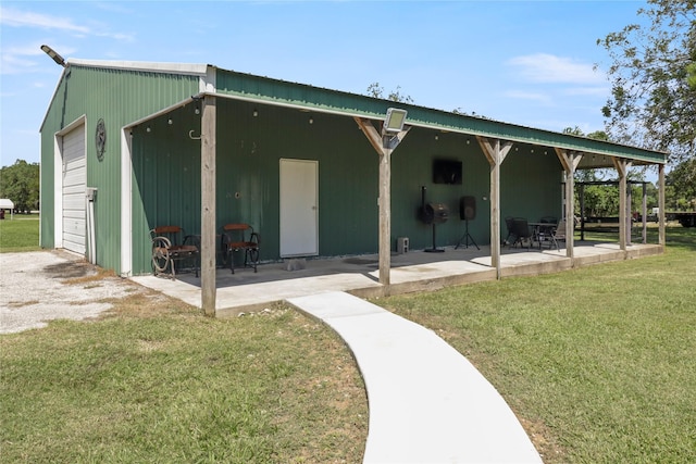 back of house featuring an outbuilding, a yard, a garage, and a patio