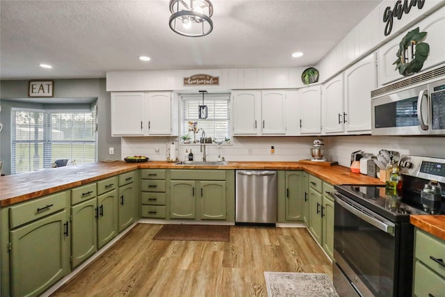 kitchen featuring stainless steel appliances, sink, green cabinets, and butcher block countertops