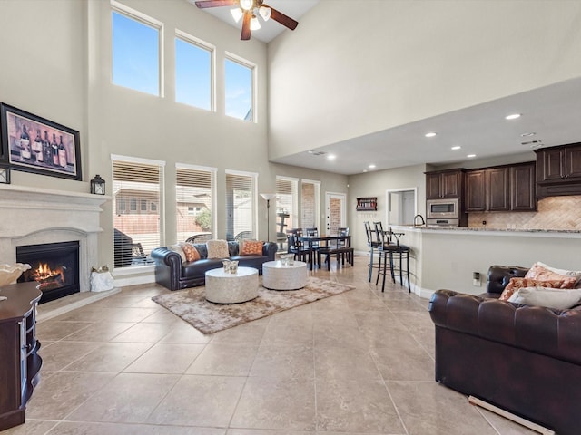 tiled living room featuring sink, plenty of natural light, a premium fireplace, and ceiling fan