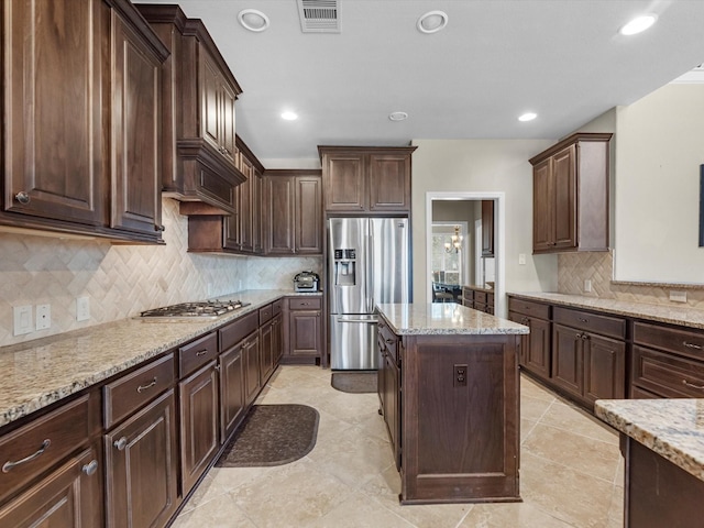 kitchen featuring light stone counters, dark brown cabinets, and appliances with stainless steel finishes