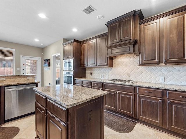 kitchen with dark brown cabinets, appliances with stainless steel finishes, and a kitchen island