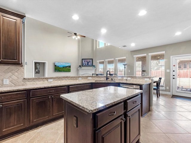 kitchen featuring sink, light stone counters, tasteful backsplash, a kitchen island, and kitchen peninsula