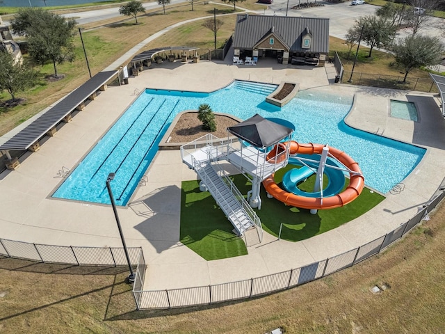 view of pool with a water slide, a playground, a patio area, and a lawn