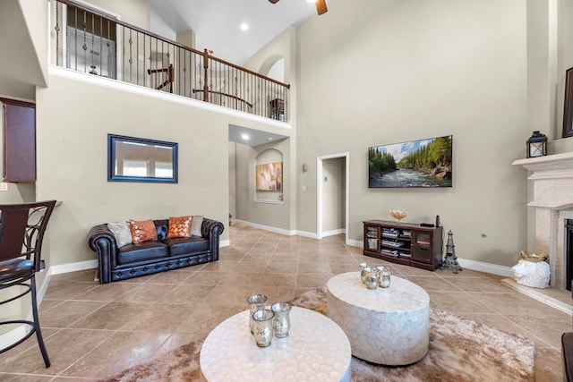 living room with a towering ceiling, ceiling fan, and light tile patterned flooring