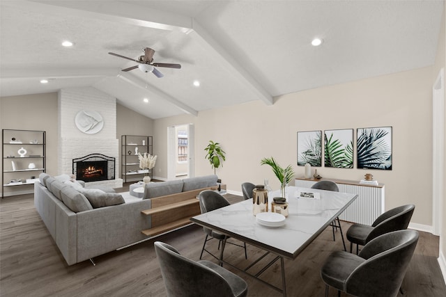 dining area featuring a fireplace, lofted ceiling with beams, dark hardwood / wood-style floors, and ceiling fan