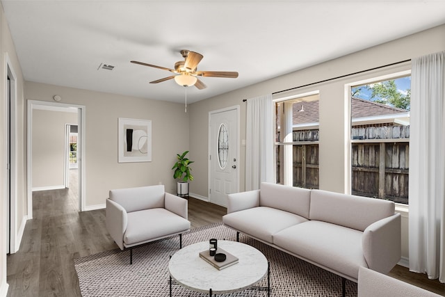 living room featuring dark wood-type flooring and ceiling fan