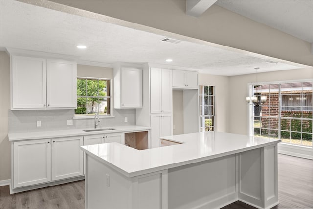 kitchen featuring white cabinetry, a large island, sink, and light hardwood / wood-style floors