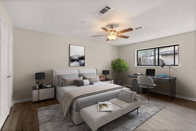 bedroom with ceiling fan, hardwood / wood-style floors, and a textured ceiling