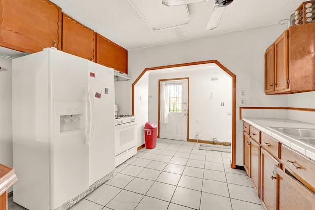 kitchen with white appliances, exhaust hood, and light tile patterned flooring