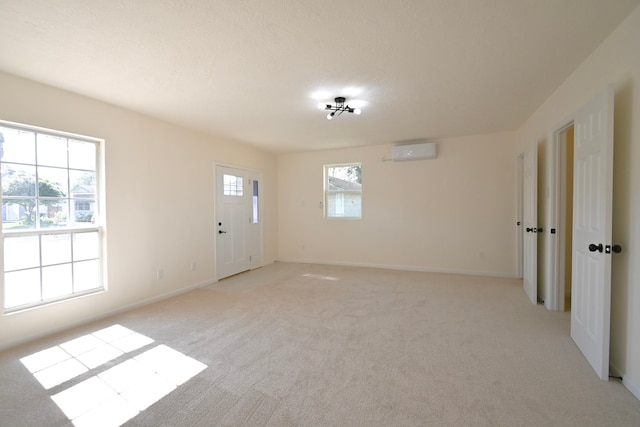 carpeted empty room featuring a wall mounted AC and a textured ceiling