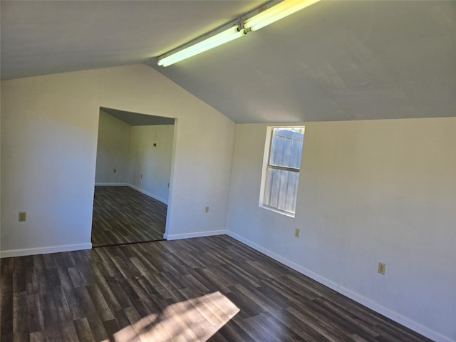 empty room with dark hardwood / wood-style flooring and vaulted ceiling