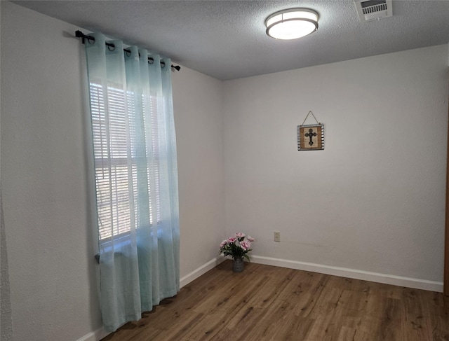 unfurnished room featuring hardwood / wood-style floors and a textured ceiling