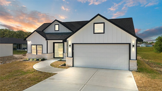 modern farmhouse style home featuring a shingled roof, concrete driveway, board and batten siding, a front yard, and a garage