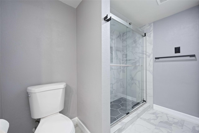 bathroom featuring a shower with door and toilet