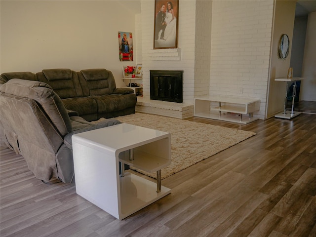 living room featuring wood-type flooring and a brick fireplace