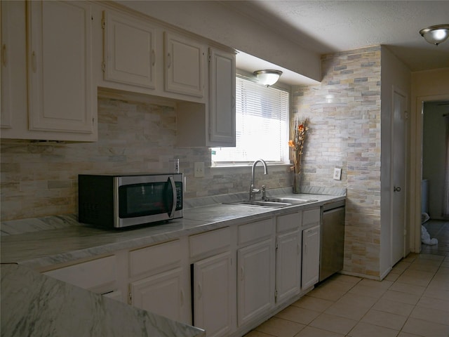 kitchen with sink, appliances with stainless steel finishes, white cabinetry, light tile patterned flooring, and decorative backsplash