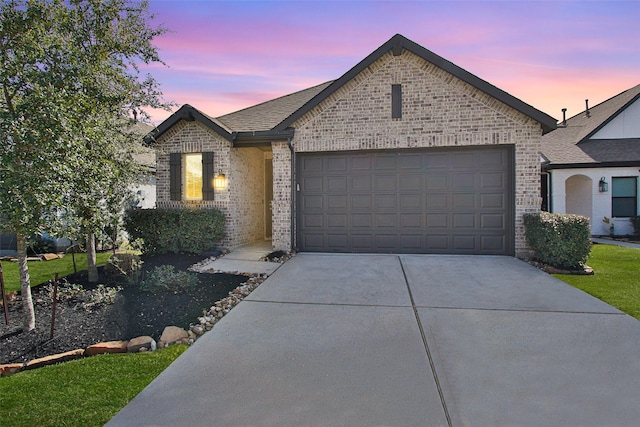 view of front of home featuring brick siding, driveway, an attached garage, and roof with shingles