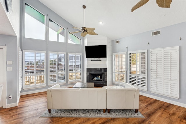 living room with a fireplace, wood finished floors, visible vents, a ceiling fan, and baseboards