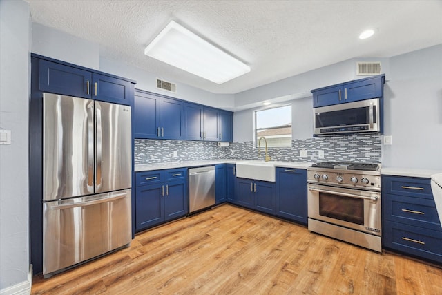 kitchen featuring stainless steel appliances, blue cabinets, a sink, and visible vents