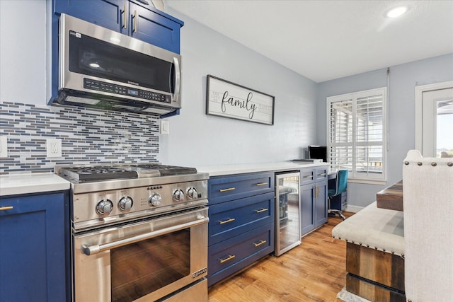 kitchen with blue cabinetry, beverage cooler, stainless steel appliances, and decorative backsplash