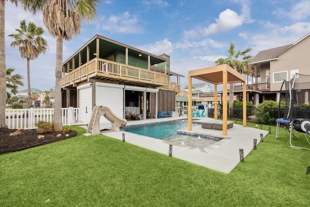 back of house featuring an outdoor pool, a patio, a trampoline, fence, and a yard