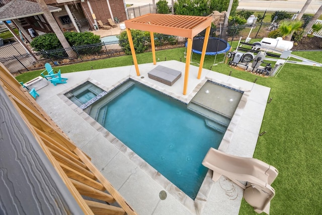 view of pool with a trampoline, a yard, a patio, a pool with connected hot tub, and fence