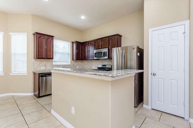 kitchen featuring a kitchen island, appliances with stainless steel finishes, decorative backsplash, light tile patterned floors, and dark brown cabinets