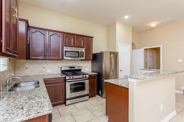 kitchen featuring a center island, appliances with stainless steel finishes, sink, and light stone counters