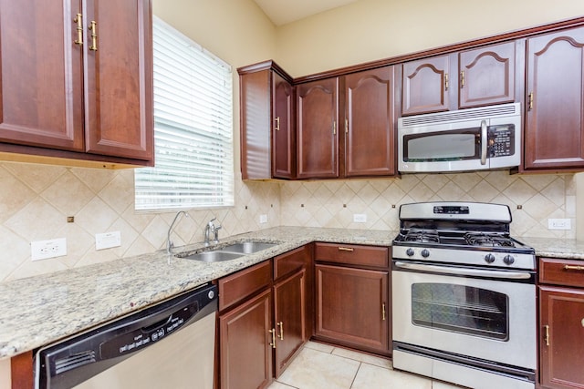 kitchen with sink, light tile patterned floors, stainless steel appliances, tasteful backsplash, and light stone countertops