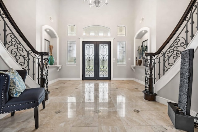 entryway featuring french doors, a notable chandelier, and a high ceiling