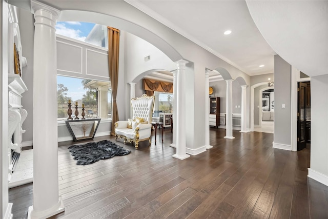 foyer entrance featuring crown molding, dark hardwood / wood-style floors, and decorative columns