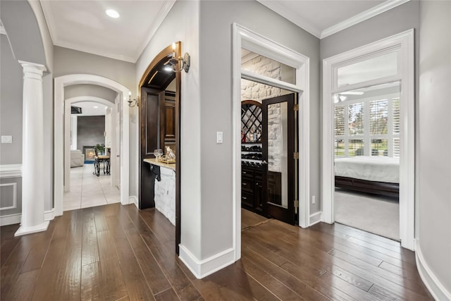 entryway with ornate columns, ornamental molding, and dark wood-type flooring