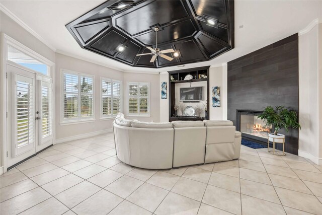 unfurnished living room with light tile patterned flooring, ornamental molding, a fireplace, and a raised ceiling