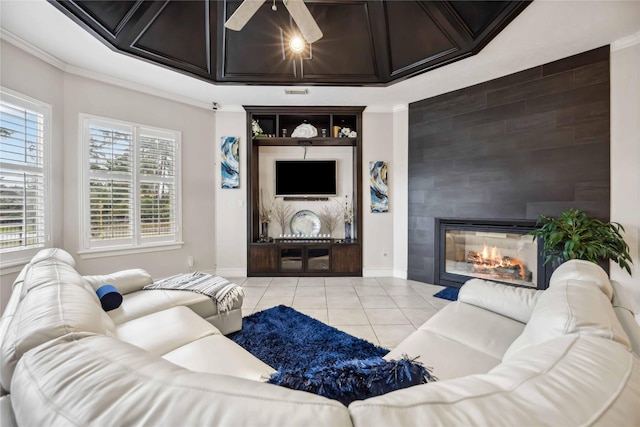 tiled living room featuring ceiling fan, a large fireplace, and ornamental molding