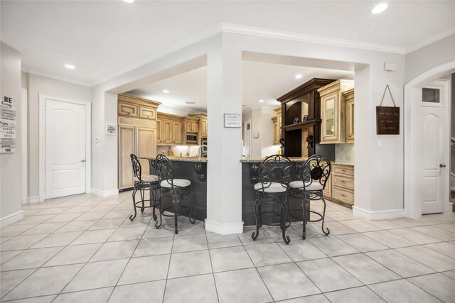 kitchen with crown molding, light stone countertops, a kitchen breakfast bar, and kitchen peninsula