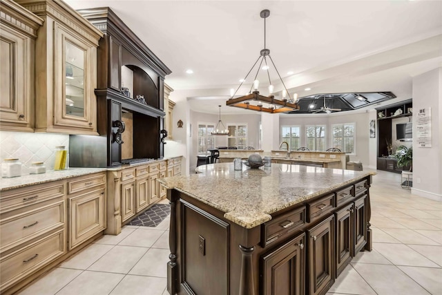 kitchen featuring light stone countertops, light tile patterned floors, decorative backsplash, and decorative light fixtures