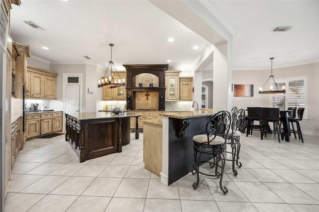 kitchen with an inviting chandelier, hanging light fixtures, light stone countertops, and a large island with sink