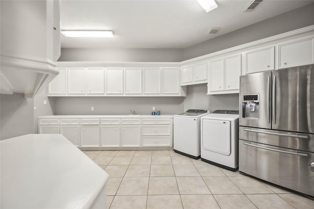 kitchen featuring light tile patterned flooring, stainless steel fridge, separate washer and dryer, and white cabinets