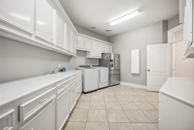 laundry room featuring cabinets, separate washer and dryer, sink, and light tile patterned floors