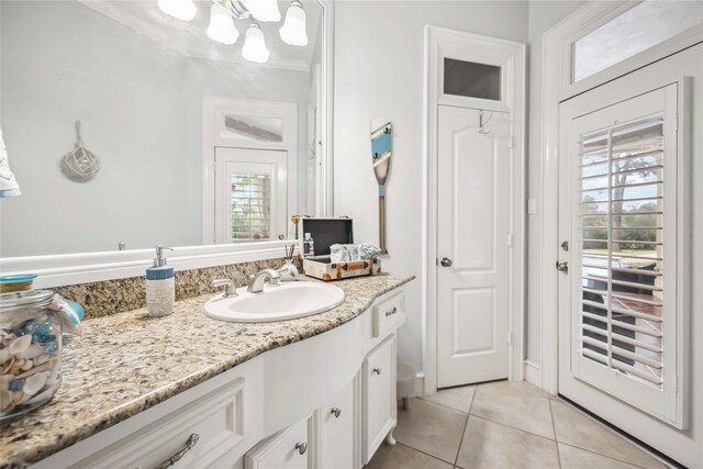 bathroom with vanity, a notable chandelier, a wealth of natural light, and tile patterned floors