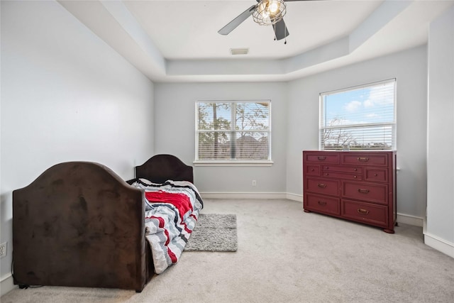 bedroom featuring ceiling fan, light colored carpet, and a tray ceiling