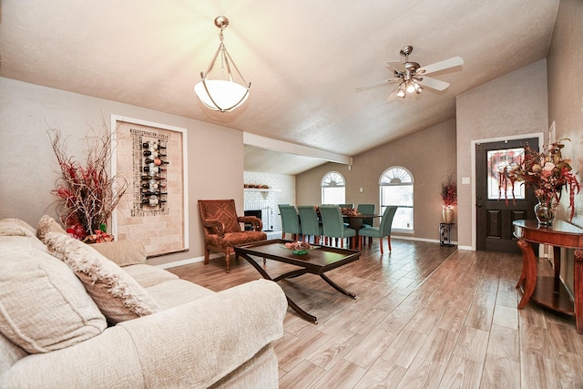 living room featuring hardwood / wood-style flooring, a brick fireplace, vaulted ceiling, and ceiling fan