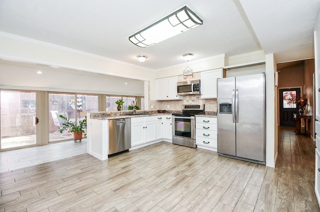 kitchen with white cabinetry, light wood-type flooring, stainless steel appliances, sink, and backsplash