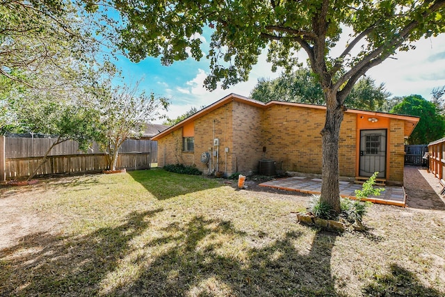 rear view of property featuring central AC unit, a yard, and a patio area