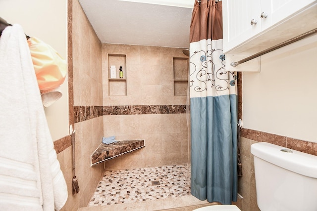 bathroom with tile walls, toilet, and walk in shower