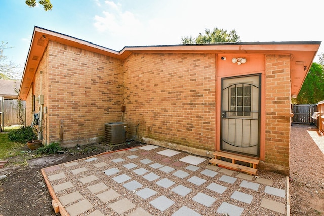 view of exterior entry featuring central AC and a patio