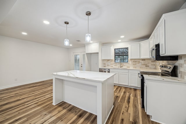 kitchen featuring sink, white cabinetry, stainless steel appliances, a center island, and decorative light fixtures