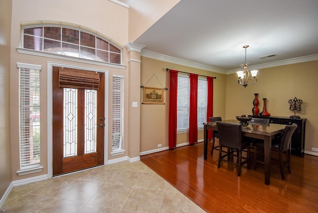 entryway featuring baseboards, visible vents, ornamental molding, wood finished floors, and a chandelier